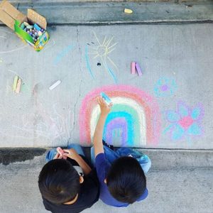 twin boys on sidewalk drawing rainbow
